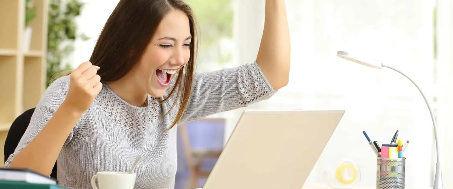 Young woman celebrating at computer