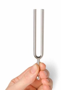 Hand holding a vibrating tuning fork, isolated on white