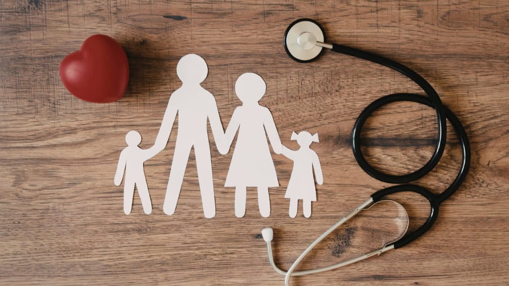 A red heart, a paper cutout of a family, and a stethoscope arranged on a wooden surface.