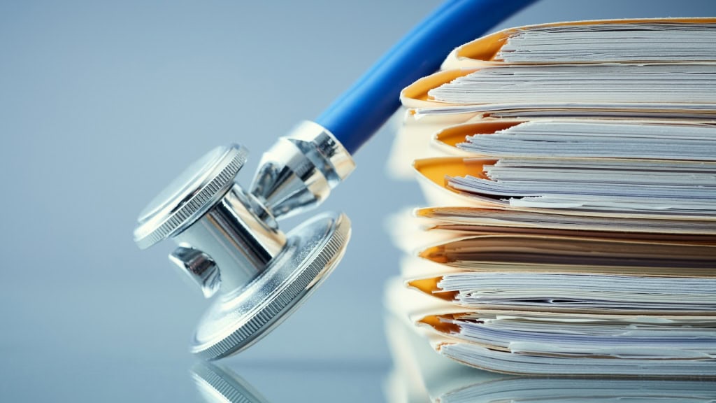 A close-up of a stethoscope resting on a stack of medical files.