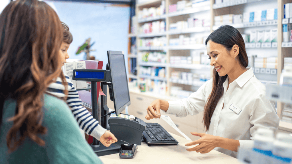 A professional pharmacy technician helping customers at pharmacy counter