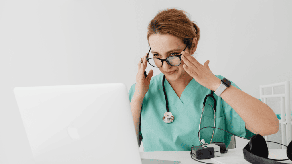 a person in scrubs sitting in front of a laptop