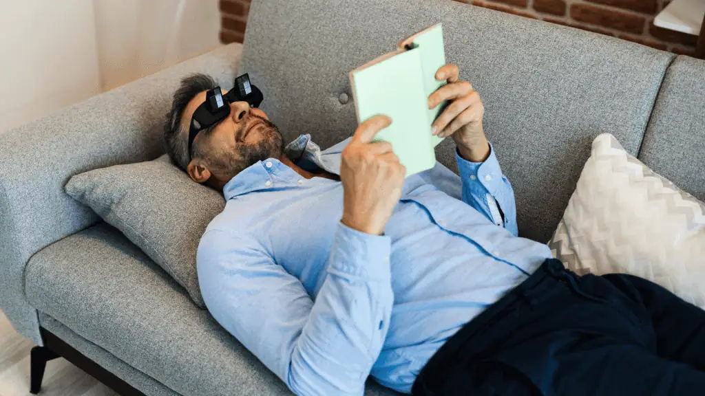 A person is reading a book while laying on a couch