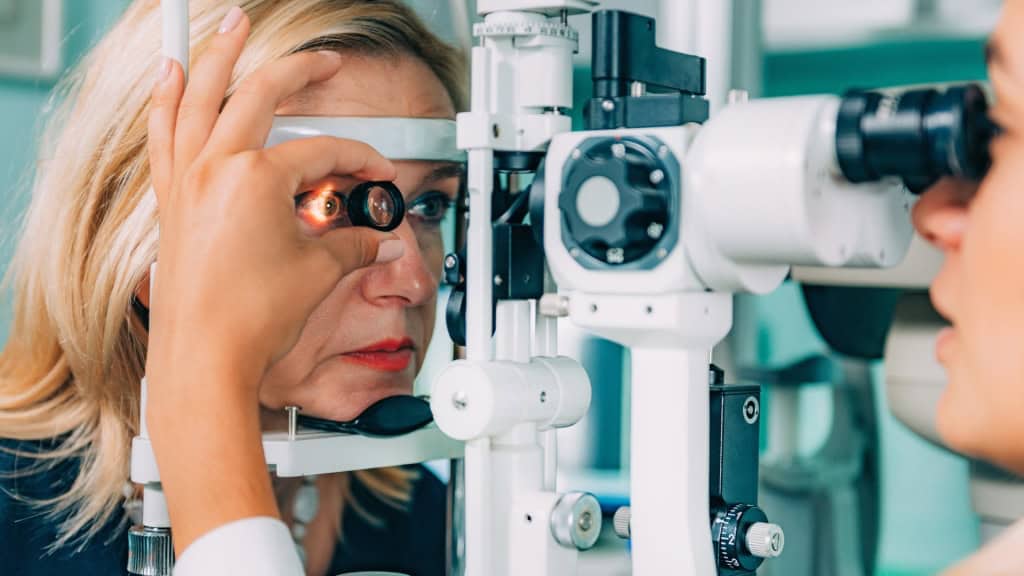 An eye care professional uses a slit lamp to examine a patient's eye.