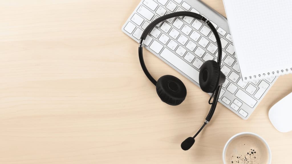 A headset sitting on top of a keyboard in a desk|Professional woman smiling