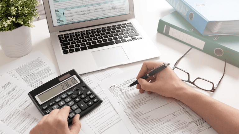 Individual filling out tax forms with calculator and laptop