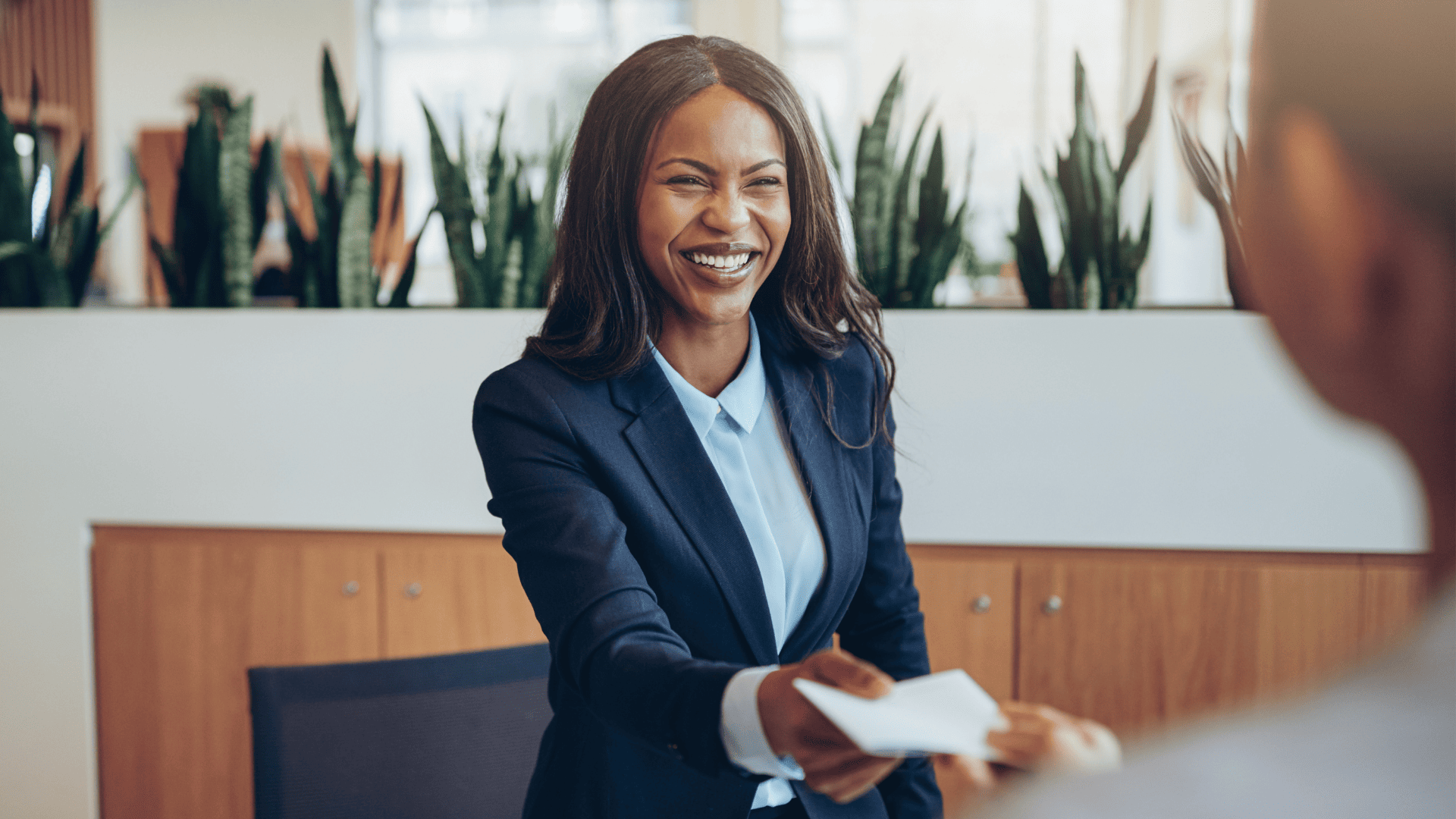 My black business woman smiling while handing a paper to employee