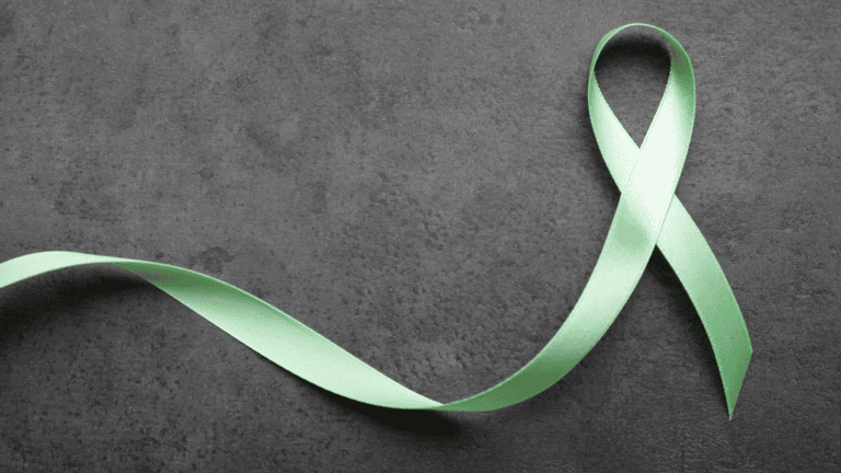 A green ribbon on a black background to represent mental health awareness